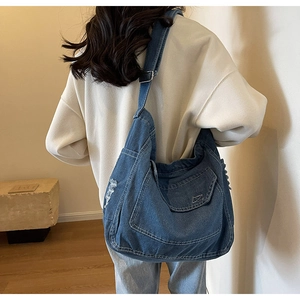 Dettaglio della borsa a tracolla in denim blu con bordi consumati e cuciture a contrasto