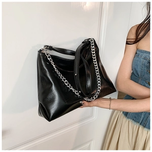Detail of black leather tote with glossy wrinkled texture and silver metal chain strap