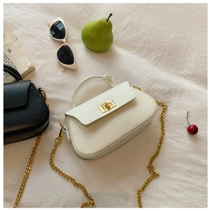 Detail of minimalist leather handbag featuring knot handle and gold chain strap in two colors