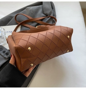 Close-up of brown pebbled leather bag base with diamond stitching and gold rivets