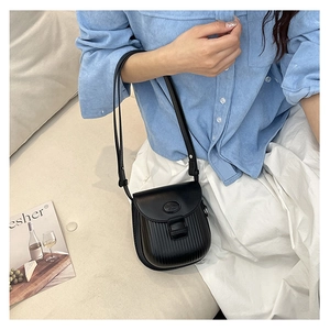Detail of black pleated crossbody bag with vertical stripe texture and smooth oval flap