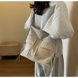 Detail of beige corduroy tote backpack with distinctive heart-shaped zip pockets