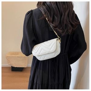 Detailed back view of model wearing a white chevron quilted bag with gold chain strap