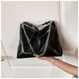 Detail of black leather hobo bag with silver chain strap and polished finish texture