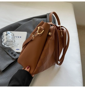 Close-up of caramel quilted leather bucket bag with golden hardware and top handle