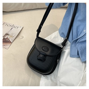 Close-up of black leather crossbody bag with vertical striped embossing and metal hardware