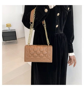 Detail of caramel PU leather crossbody bag with elegant gold chain and embossed texture
