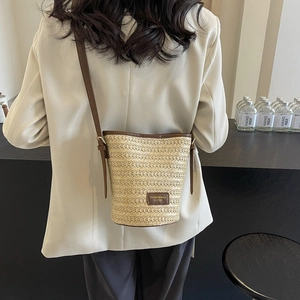 Women's hand-woven straw bucket bag with brown leather trim and adjustable strap for summer