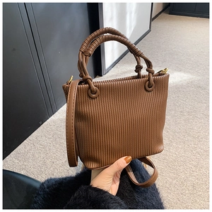 Detail of vertical pleated texture and knotted handle on brown vintage bucket bag
