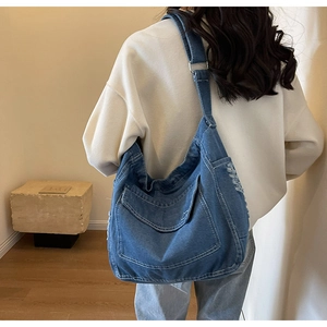 Dettaglio borsa in denim blu con bordi sfrangiati, tasche grandi e tracolla regolabile