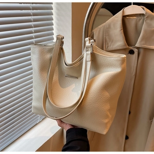 Detail view of cream white tote bag with lychee texture and silver metal bar accessory