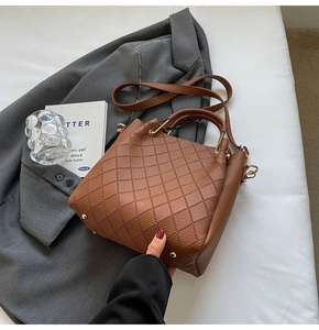 Detail of caramel brown quilted bucket bag with leather texture and metal bottom studs