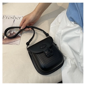 Detail of black crossbody bag with pleated texture and stylish oval fashion badge