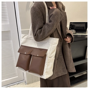 Detail of canvas tote bag showing dark brown leather flap pockets and retro design