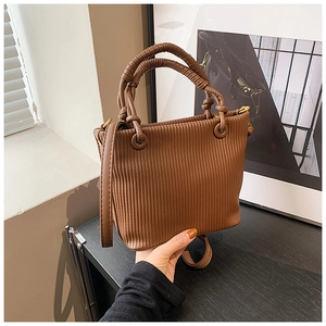 Detail of brown pleated bucket bag with unique woven handles and golden hardware accents
