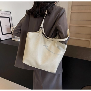 Detail view of cream pebble leather tote bag with elegant silver metallic bar detail