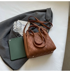 Detail of caramel brown bucket bag featuring diamond quilting and gold hardware