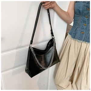 Macro shot of a black slouchy hobo bag featuring shiny wrinkled leather and a bold silver chain