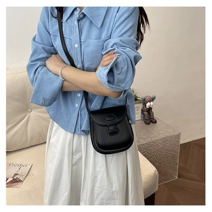 Detailed close-up of a black textured crossbody bag with vertical pleated patterns
