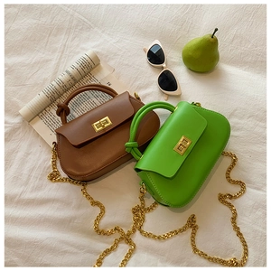 Flat lay of mini vegan leather crossbody bags in brown and green with gold chain straps