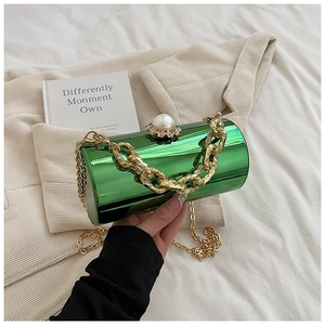 Detail of green acrylic cylinder bag with pearl clasp and golden chain straps