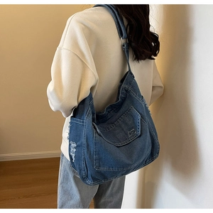Modella indossa una grande borsa tote in denim blu con dettagli sfrangiati e fibbia