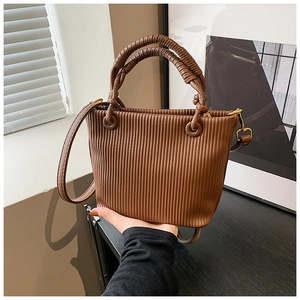 Detail of brown pleated bucket bag showing vertical texture and gold hardware accessories