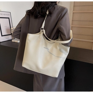 Detailed shot of beige lychee pattern tote bag with silver metal trim on a model