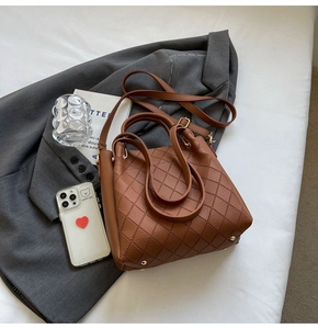 Close-up of caramel brown woven leather bucket bag with gold hardware and metal feet
