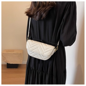 Detail of white chevron quilted crossbody bag on a black dress with golden hardware