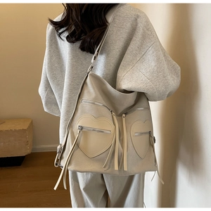 Detail of off-white corduroy backpack with heart-shaped pockets and leather tassels