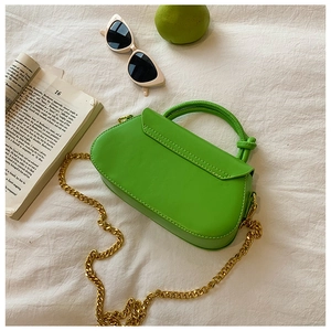 Top view of bright green leather handbag with knotted handle and chunky gold chain