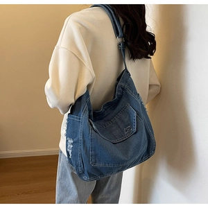 Dettaglio della borsa a tracolla in denim blu con bordi sfrangiati e cuciture a contrasto