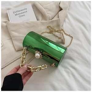 Macro detail of cylindrical green metallic box bag with gold chain and pearl closure