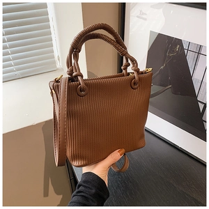 Detail of coffee brown bucket bag with pleated texture and thick spiral woven handle