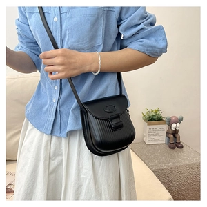 Detail of black crossbody bag featuring vertical embossed stripes and matte texture