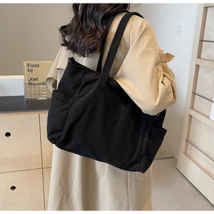 Detail view of black corduroy tote bag side pocket on model in lifestyle setting