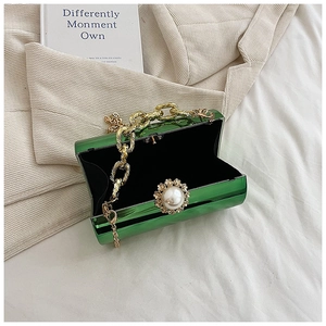 Close-up of green acrylic cylinder bag with gold chain and large pearl flower clasp