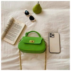 Detailed flat lay of a bright green leather handbag with gold chain and trendy accessories