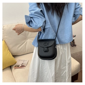 Chic black crossbody bag with vertical stripe texture worn by a model in casual setting