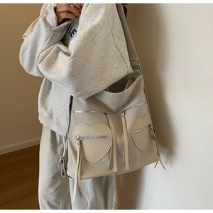Detail of beige canvas backpack featuring two symmetrical heart-shaped zipper pockets