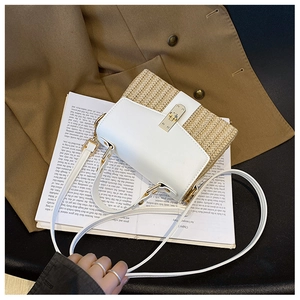 Nahaufnahme der gewebten Stroh- und weißen Ledertasche mit goldenem Metalldrehverschluss