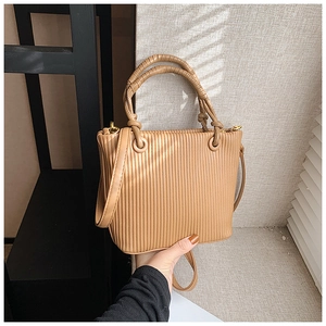 Detailed view of the vertical pleated texture and golden hardware on this khaki bucket bag