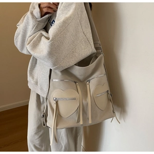 Detail of off-white corduroy backpack featuring heart-shaped pockets and fringe tassels