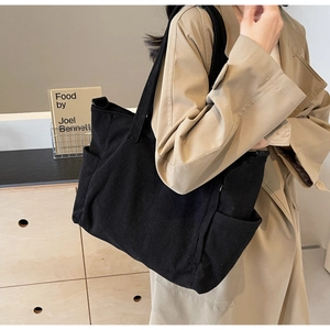 Detail of black corduroy tote bag showing side storage pocket and ribbed texture