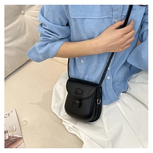 Close-up of black crossbody saddle bag with pleated texture and stylish matte finish