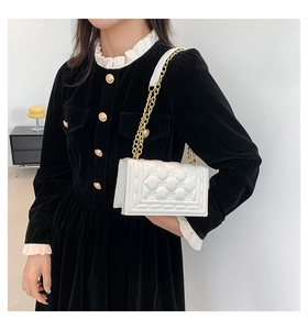 Detailed close-up of white quilted leather chain bag and premium gold-tone metal hardware