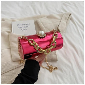 Detail of cylinder evening bag with rose red mirror finish and gold chain strap