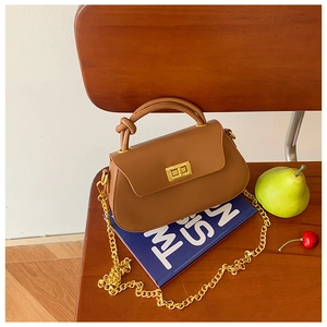 Detailed view of brown retro leather handbag with gold twist lock and metal chain on chair