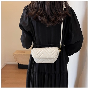 Detail view of white quilted leather crossbody bag with elegant V-shaped stitching pattern